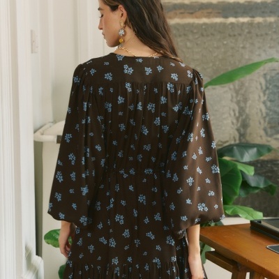 Veste castanha com flores azuis vista de costas em ambiente interior