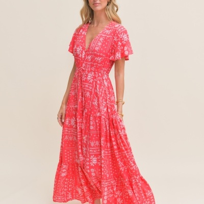 Vestido longo coral com padrão branco floral e geométrico.