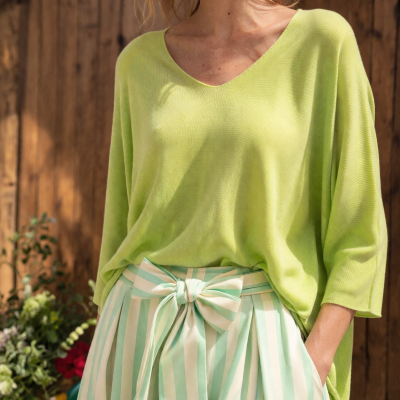 Mulher com camisola verde-limão e saia com riscas verde-pálido e branco com laço.