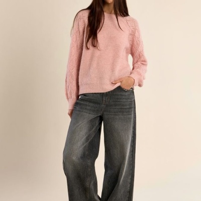 Mulher com camisola rosa de malha e calças largas de ganga cinza