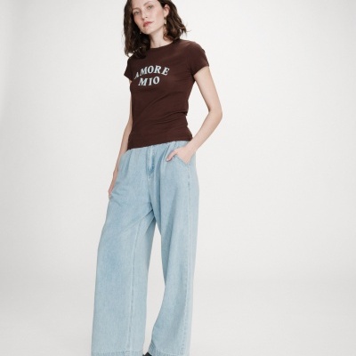 Mulher com camisola castanha AMORE MIO e calças largas de ganga azul clara