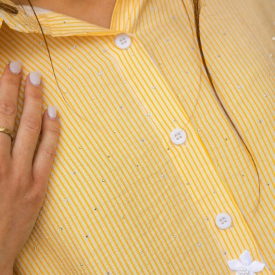 Camisa de riscas amarelas e brancas com botões brancos e pérolas decorativas.