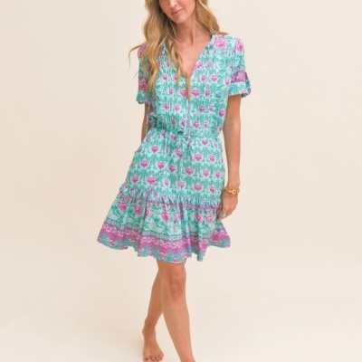 Vestido curto floral verde, rosa e roxo com cintura ajustável em fundo neutro