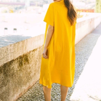 Vestido amarelo de manga curta usado por mulher com sapatos castanhos em ambiente exterior