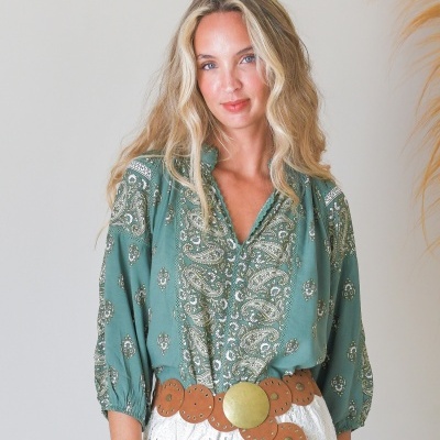 Blusa verde com padrão floral e cinto castanho de couro com aplicações metálicas