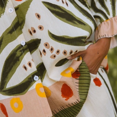 Camisa com padrão floral em tons de verde, amarelo e laranja, botões brancos e punho franzido