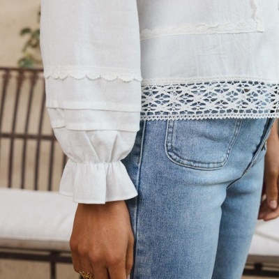 Blusa branca em tecido com renda combinada com calças de ganga azuis claras.