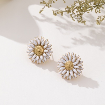 Brincos flor branco com centro dourado sobre fundo branco e ramo seco