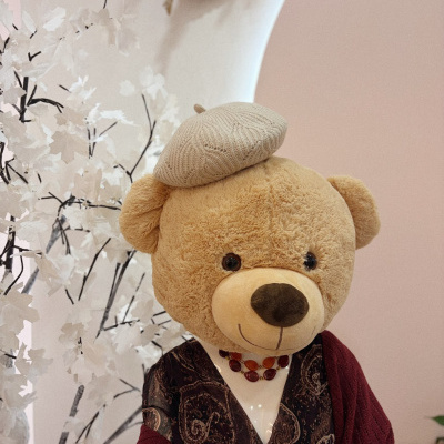 Urso de peluche com roupa e boina sentado em ambiente decorativo