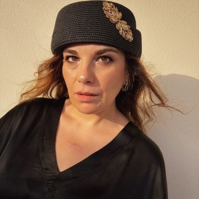 Mulher com chapéu preto de corda trançada com aplicação dourada