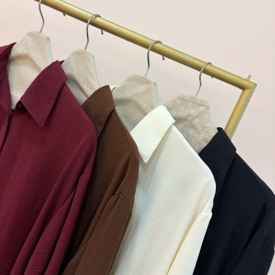 Quatro camisas coloridas penduradas em cabides numa estrutura dourada