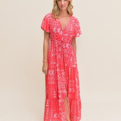 Vestido vermelho comprido com estampado branco usado por mulher em fundo neutro