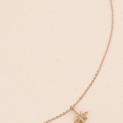 Colar dourado com pingente de estrela de oito pontas e cristal