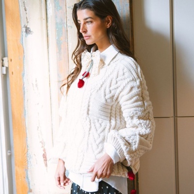 Mulher vestindo camisa branca, camisola de malha creme e saia preta com bolinhas