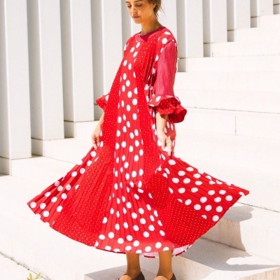 Mulher com vestido vermelho de bolinhas brancas em escadas ao ar livre