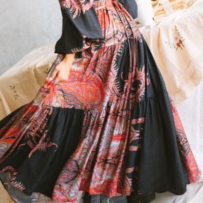 Vestido longo estampado com padrão floral e paisley em tons de vermelho, laranja e preto.