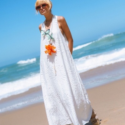 Vestido longo branco com estampa colorida de borboleta e flor, usado na praia