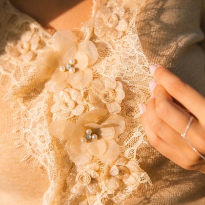 Tecido bege com renda e flores decorativas em detalhe