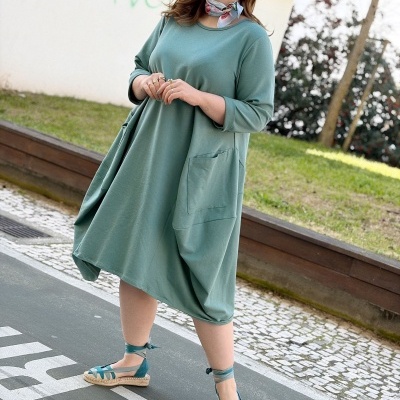 Mulher vestindo vestido verde água com bolsos e sandálias azuis posando ao ar livre