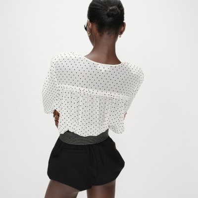 Blusa branca com bolinhas pretas e calções pretos vista de costas