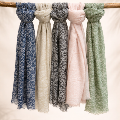 Conjunto de lenços coloridos com padrão de folhas pendurados numa vara de madeira