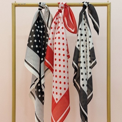 Três lenços com padrão de bolinhas pendurados num cabide dourado