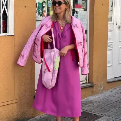 Mulher com vestido rosa e casaco rosa claro pendurado nos ombros