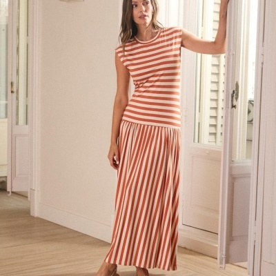 Vestido longo com riscas creme e terracota numa sala interior