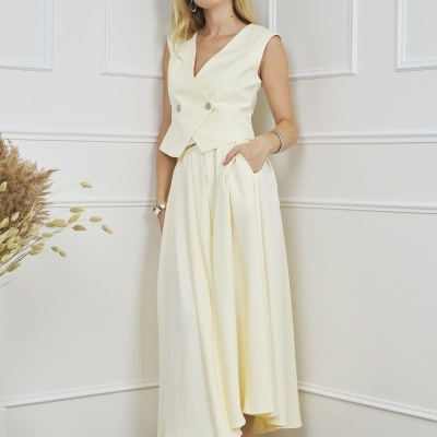 Conjunto feminino creme com colete e saia, sapatos de salto creme, parede branca interior