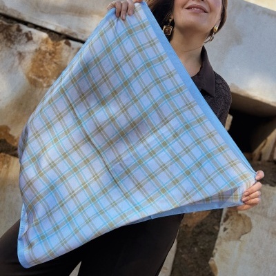 Mulher sorridente segurando lenço xadrez azul e verde
