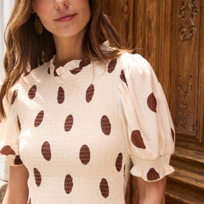 Vestido creme com bolas castanhas e mangas bufantes curto, com gola folhada.
