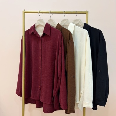 Camisas texturizadas em quatro cores penduradas em cabide dourado
