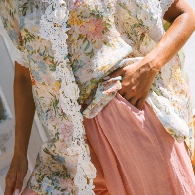 Blusa floral feminina com renda branca e calças cor de salmão ao sol