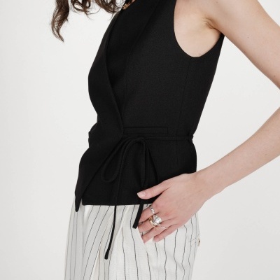 Blusa preta sem mangas com cinto fino e calças brancas riscas pretas
