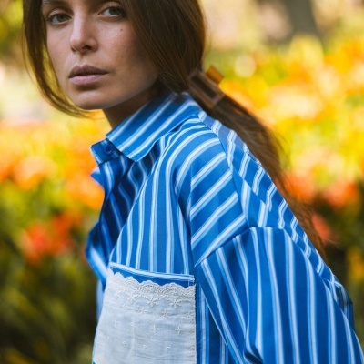 Camisa azul às riscas com bolso branco bordado usada por mulher com cabelo preso