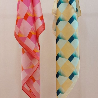 Lenços geométricos rosa e amarelo pendurados em parede clara