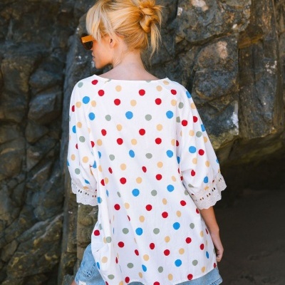 Blusa branca com bolinhas coloridas e renda nas mangas, vista de costas