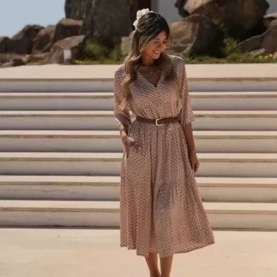Mulher com vestido midi padrão geométrico beige e castanho com cinto castanho e sandálias castanhas claras
