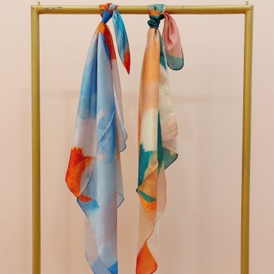 Dois lenços finos coloridos pendurados em cabide dourado