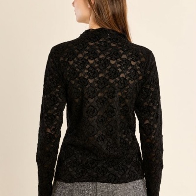 Blusa preta em renda floral com calças cinzentas vista de costas