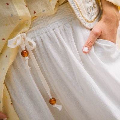 Parte inferior de roupa feminina branca com cordões, camisa amarela com corações e colete bordado