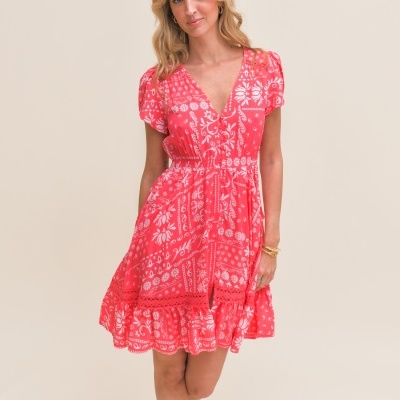 Vestido curto rosa com padrão branco floral e geométrico com decote em V e folho na barra