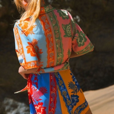Vestido curto colorido com padrão floral e geométrico visto de costas.