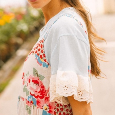 Mulher com vestido floral colorido e t-shirt branca com renda na manga