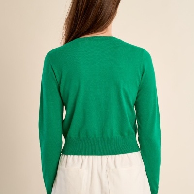 Camisola de malha verde de manga comprida vista de costas com calças brancas largas.