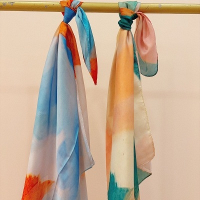 Dois lenços coloridos pendurados numa barra metálica amarela