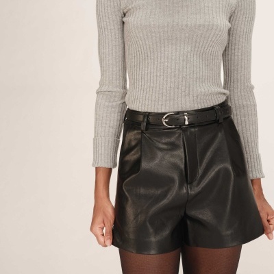 Pessoa com camisola cinza canelada e calções pretos de couro com cinto preto.