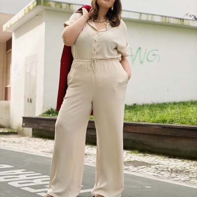 Mulher a usar macacão bege claro com botões dourados e casaco vermelho pendurado no ombro em rua urbana