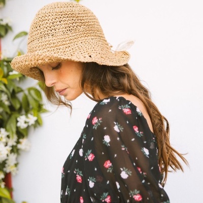 Mulher com chapéu de palha bege e vestido floral preto