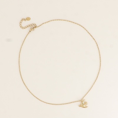 Colar dourado com pendente de pássaro sobre fundo bege.